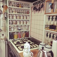 a stove top oven sitting inside of a kitchen next to a wall filled with pots and pans