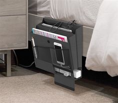 a magazine holder is placed on the floor next to a bed