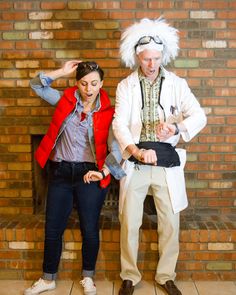 two people in costumes standing next to each other near a brick wall and fire place