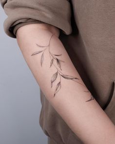 a woman with a tattoo on her arm that has leaves coming out of the arm