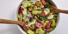 a salad in a white bowl with wooden spoons on the side, ready to be eaten