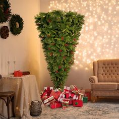 a christmas tree with presents under it in front of a couch and table set up