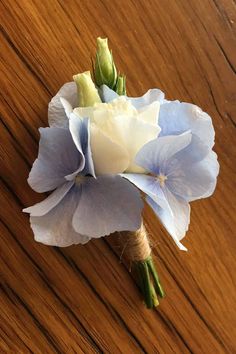 blue and white flowers are sitting on a wooden table with wood grain in the background