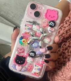 a person holding a cell phone case with various stickers on it