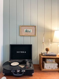 a record player sitting on top of a wooden table next to a lamp and pictures