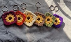 four crocheted flower keychains are shown on a gray sheet with white background