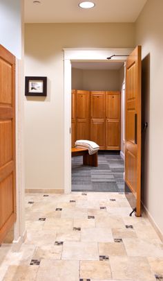 an empty hallway with wooden doors leading to another room and a bench on the other side