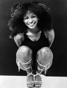 an old photo of a woman with big afros on her head and legs, smiling