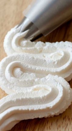 two pieces of white cake sitting on top of a wooden table next to a knife