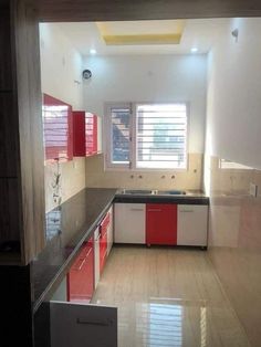 an empty kitchen with red and white cabinetry, counter tops, and cabinets in it