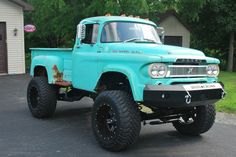 an old blue truck parked in front of a house