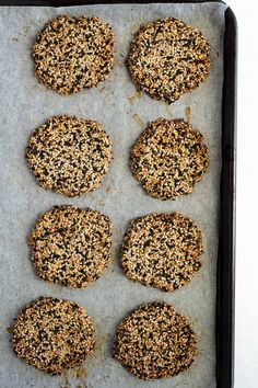 six cookies on a baking sheet ready to go into the oven, with oats sprinkled on top