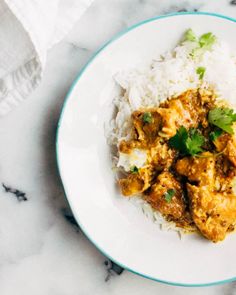 a white plate topped with rice and meat covered in cilantro next to a napkin