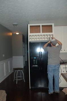 a man standing next to a refrigerator in a kitchen