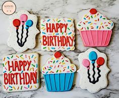 decorated cookies with happy birthday written on them sitting on a marble countertop next to each other