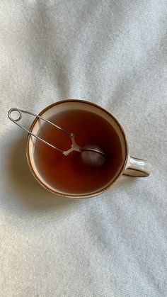 a cup of tea with a spoon in it sitting on a white cloth covered table