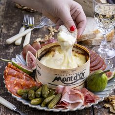 a person is dipping cheese into a bowl of soup with meats and vegetables on the side