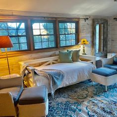 a bed room with a neatly made bed next to two chairs and a couch in front of a window