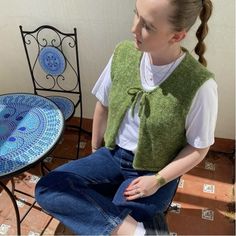 a woman sitting on top of a chair next to a table