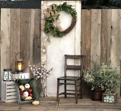 an outdoor area with wooden fence, chairs and wreath on the wall next to potted plants