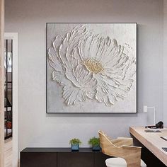 a large white flower is hanging on the wall above a desk in an office space