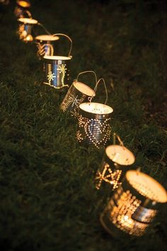 some tin cans are lined up in the grass with lights on them and one is empty