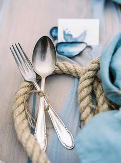 there is a fork, knife and spoon on the table with blue napkins next to it