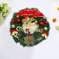 a christmas wreath with bells and decorations around it on a table next to some flowers