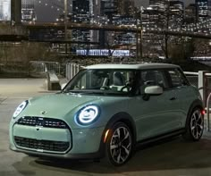 a small car is parked in front of a cityscape with the lights on