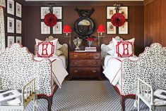 two beds in a room with pictures on the wall and one bed has red pillows