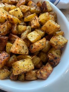 a white bowl filled with cooked potatoes on top of a table next to a blue and white towel