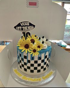 a cake decorated with sunflowers and blue icing on top of a white box