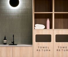 a bathroom with wooden cabinets and towels on the shelf next to it is lit by a round light