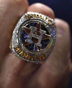 a man's hand holding a ring with an image of a cross on it