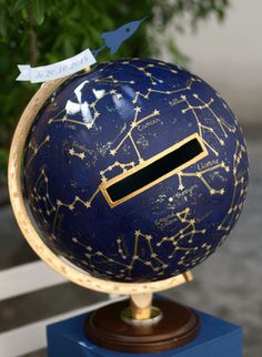 a blue and gold globe with stars on it sitting on top of a wooden block