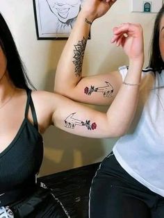 two women with tattoos on their arms and one is pointing at the other woman's arm