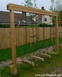 a wooden swing set with swings in the grass