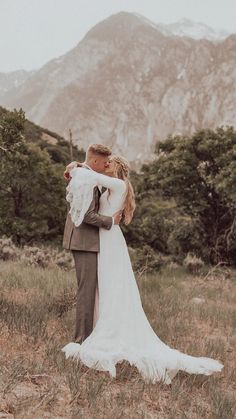 a bride and groom embracing in the mountains