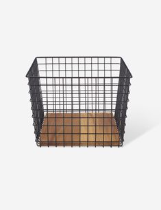 a black wire basket with wood flooring on the bottom and sides, against a white background