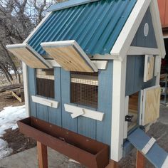 a blue and white chicken coop with windows