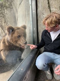 a man pointing at a bear through a glass window