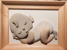 there is a stone sculpture of a koala sleeping on it's side in a wooden frame