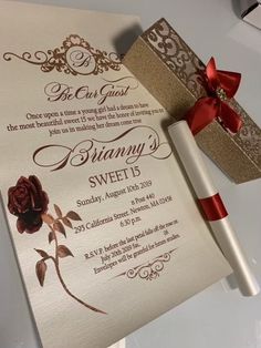 an elegant wedding card with a red ribbon tied around it and a gift box next to it