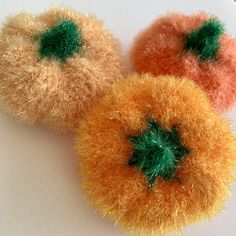 three orange and green pom - poms sitting on top of a white surface