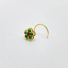 a pair of green and red earrings on a white surface with one earring in the shape of a flower