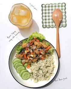 a white plate topped with rice and meat next to a wooden spoon on top of a table