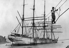 an old black and white photo of a man standing on the top of a ship