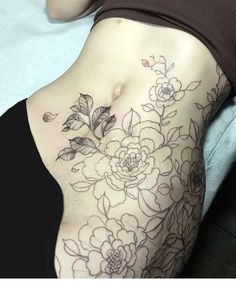 a woman's stomach with flowers and leaves on the side, as if it were tattooing