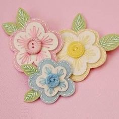 three different colored flowers on a pink background