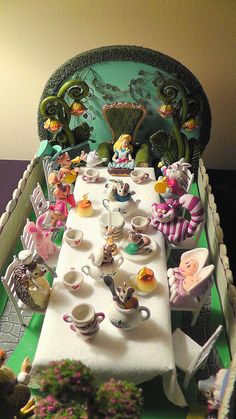 a table set up for a tea party with figurines on it